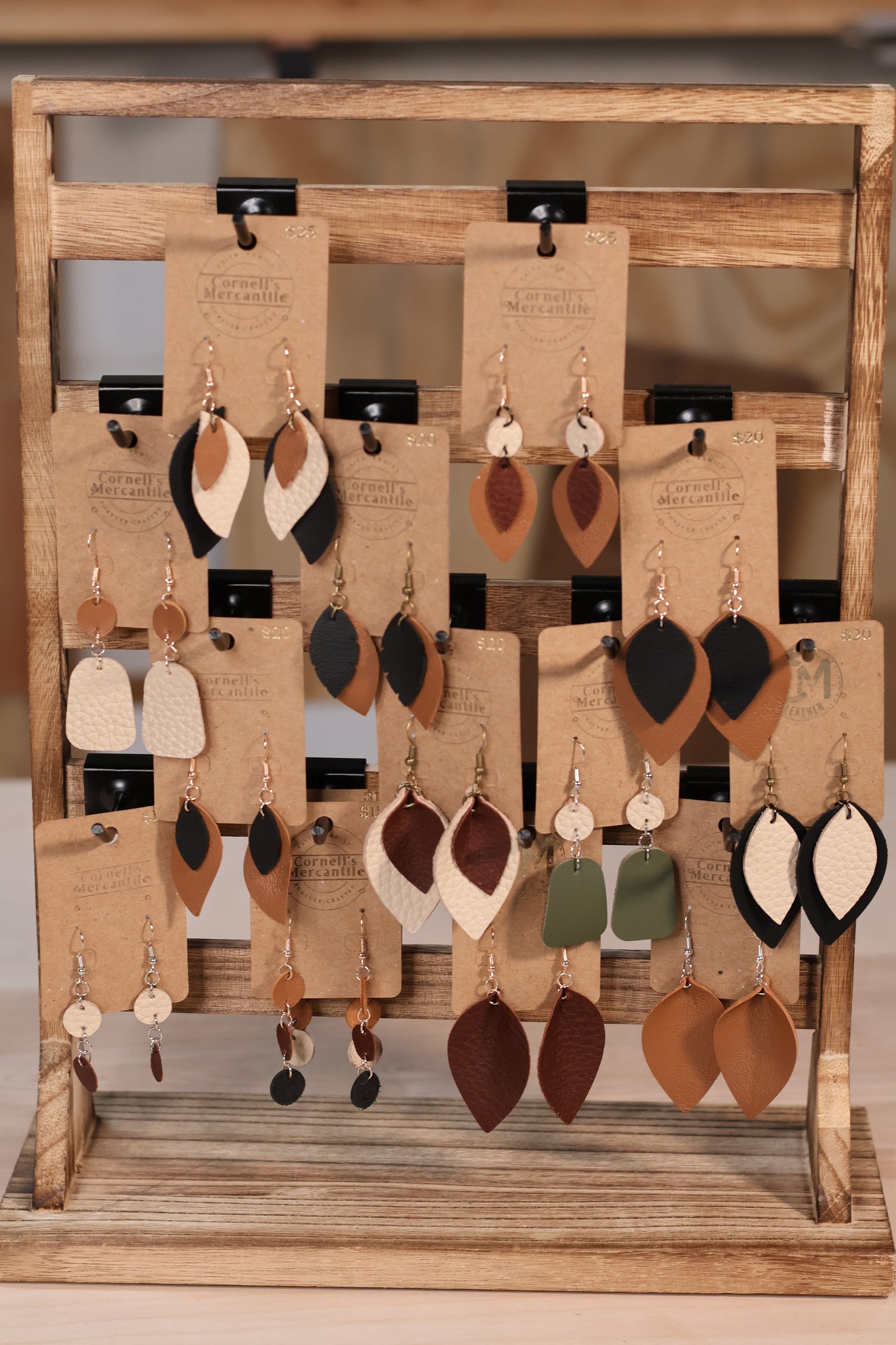 Collection of earrings displayed on a wooden rack with cards underneath.
