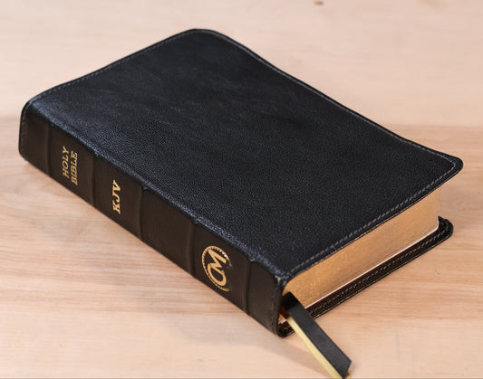 Black leather-bound book with gold embossed lettering on a wooden surface